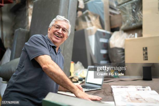 portrait of a senior man using digital tablet in an upholstery workshop - upholstery worker stock pictures, royalty-free photos & images