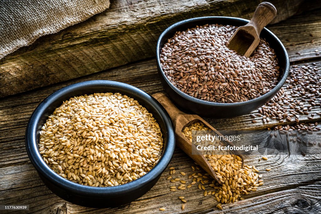 Flax seeds in a black bowl on rustic wooden background