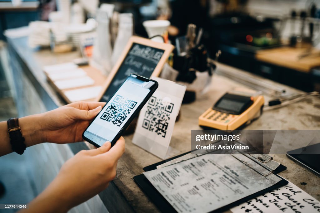 Kunden scannen QR-Code, machen eine schnelle und einfache kontaktlose Zahlung mit ihrem Smartphone in einem Café