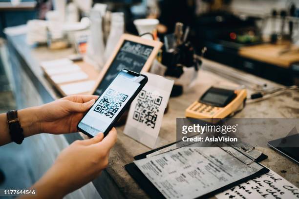 customer scanning qr code, making a quick and easy contactless payment with her smartphone in a cafe - paying stock pictures, royalty-free photos & images