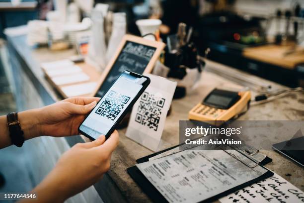customer scanning qr code, making a quick and easy contactless payment with her smartphone in a cafe - código-de-barras imagens e fotografias de stock