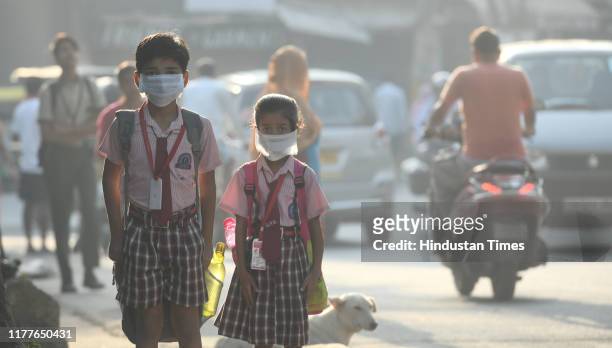 Students cover their faces with masks to protect themselves from morning air pollution, at Mayur Vihar on October 22, 2019 in New Delhi, India. A...