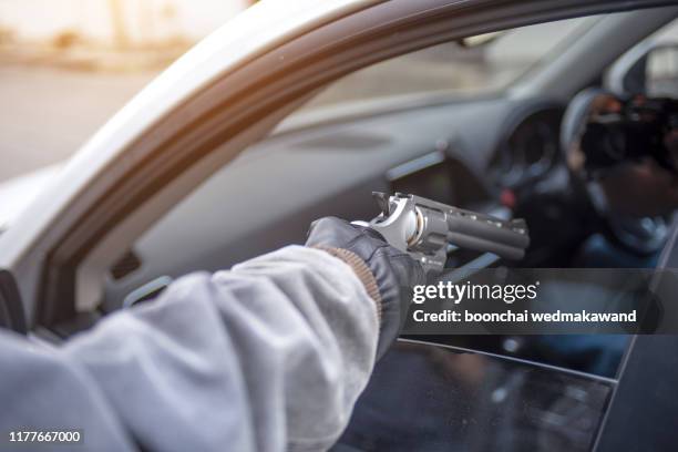 gangster with a gun trying to rob a guy which is sitting in his car. - kapen stockfoto's en -beelden