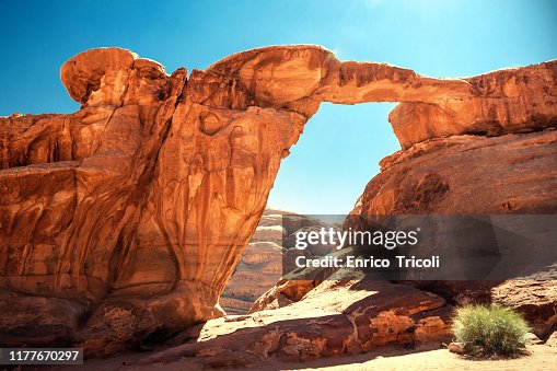 Jordan: rock bridge in the Wadi Rum desert; very warm colors on yellow and red during sunset. Background, wallpaper.