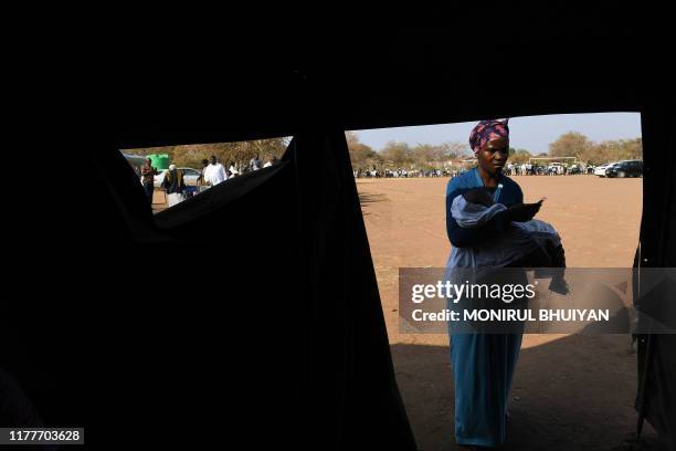 Woman holding a baby walks into a tent to cast her vote at a polling station in Gaborone on October 23, 2019. - The general election happens in...