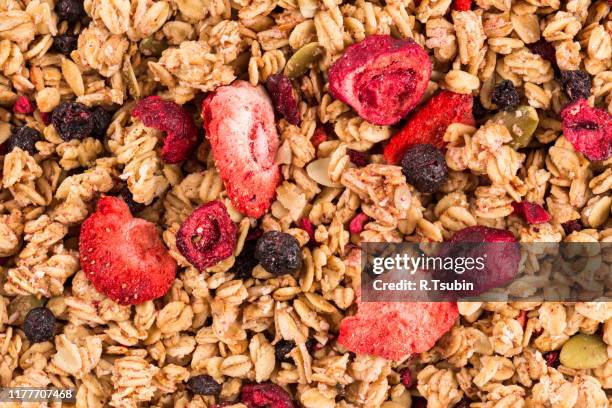 muesli cereals close up background with  raisins, oat and wheat flakes, fruits, strawberry, cranberry, cherry pieces - muesli stock pictures, royalty-free photos & images