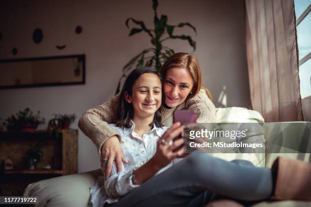mor och dotter med hjälp av en smartphone - family teenager home life bildbanksfoton och bilder