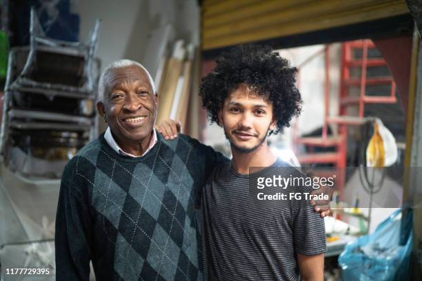 porträt von kollegen, die in einer polsterwerkstatt stehen - family business - african american grandfather stock-fotos und bilder
