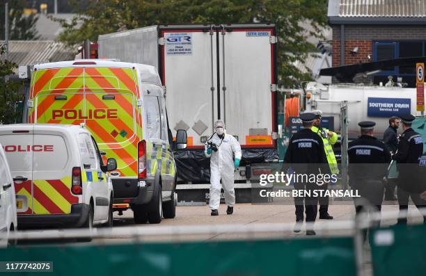 British Police officers in forsensic suits work near a lorry, found to be containing 39 dead bodies, as they work inside a police cordon at...