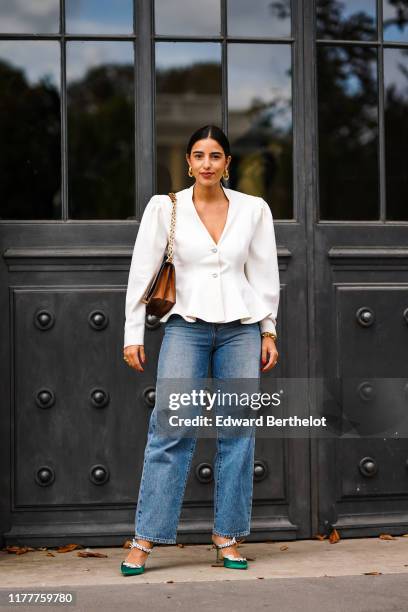 Bettina Looney wears a white ruffled jacket, blue large jeans, green shoes, a brown bag, outside Elie Saab, during Paris Fashion Week - Womenswear...