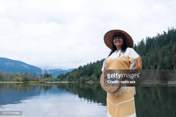 eine ältere indigene kanadierin steht mit ihrem musikinstrument - kanadische kultur stock-fotos und bilder
