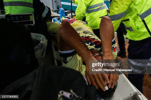 Giovani Dos Santos of America is taken out the field while he is crying after being injured during the 12th round match between America and Chivas as...