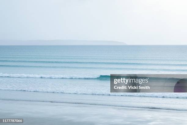 calm blue ocean waters with surf swell on a misty morning - escena de tranquilidad fotografías e imágenes de stock