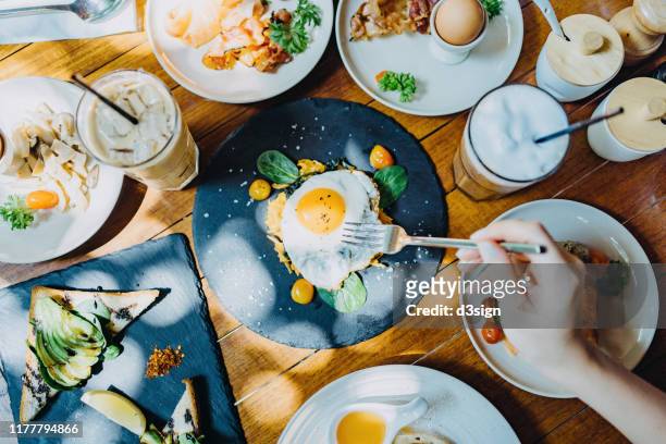 directly above view of woman sharing a variation of meal in an outdoor restaurant against beautiful sunlight - breakfast eggs stockfoto's en -beelden