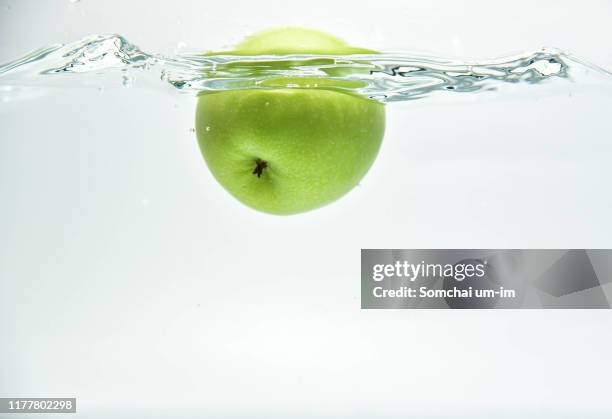 green apple in the water splash - apple water splashing stock-fotos und bilder