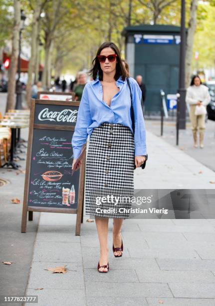 Guest is seen wearing blue button shirt, plaid skirt outside Altuzarra during Paris Fashion Week Womenswear Spring Summer 2020 on September 28, 2019...