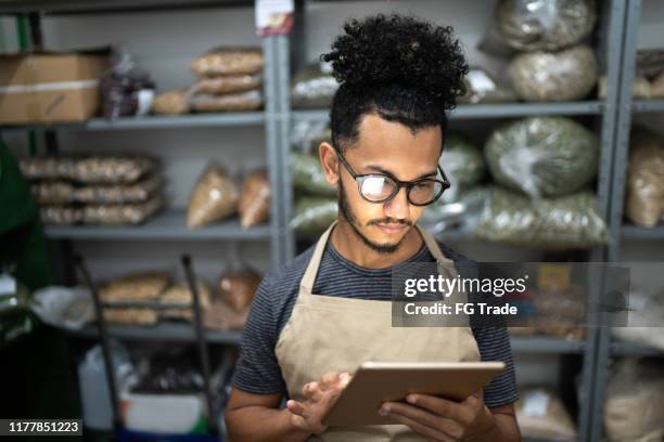 männer mit digitalem tablet im lagerraum eines naturprodukt-shops - lagerraum stock-fotos und bilder