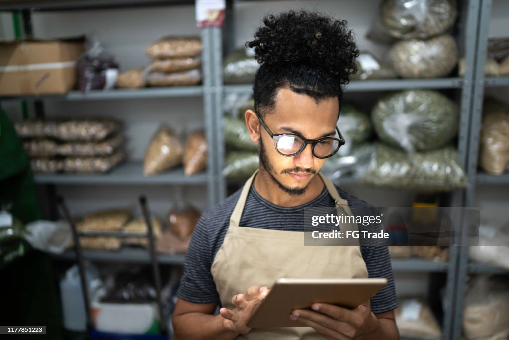 Men using digital tablet in storage room of a natural product shop