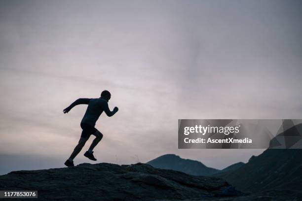 cross country runner bounds up mountain - striding stock pictures, royalty-free photos & images