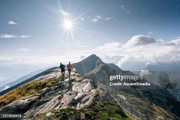 paar wanderung in der hellen sonne auf einem bergrücken - swiss mountain stock-fotos und bilder