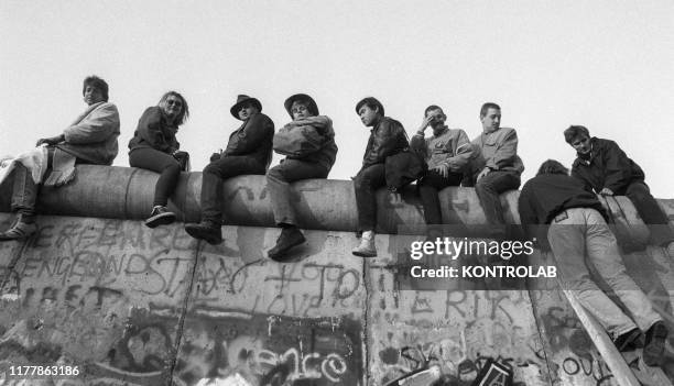 People seat on top of the wall on November 10, 1989 the day after the collapse of the Berlin Wall.