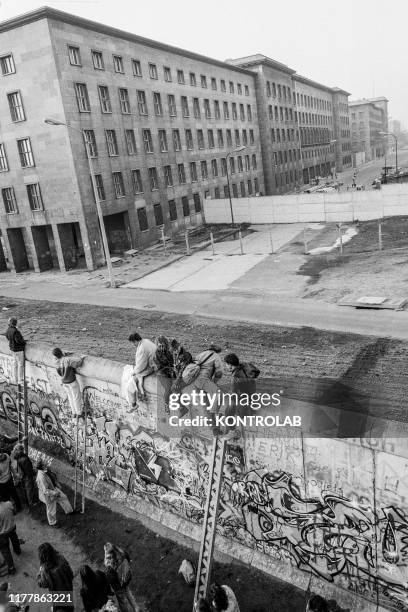 People stay on top of the wall on November 10, 1989 the day after the collapse of the Berlin Wall.