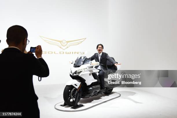 An attendee poses for a photograph on a Honda Motor Co. Goldwing motorcycle at the Tokyo Motor Show in Tokyo, Japan, on Thursday, Oct. 24, 2019. From...