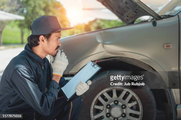 mechanic inspecting damaged vehicle - abollado fotografías e imágenes de stock