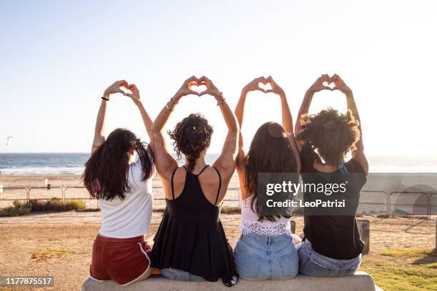 gelukkige jonge vrouwen die plezier hebben op het strand - alleen jonge vrouwen stockfoto's en -beelden