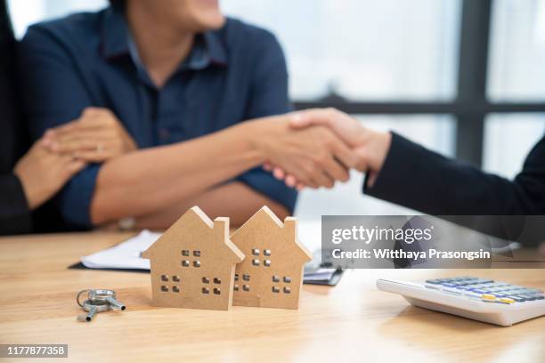 real estate agent and customers shaking hands together celebrating finished contract - mortgage agreement stock pictures, royalty-free photos & images