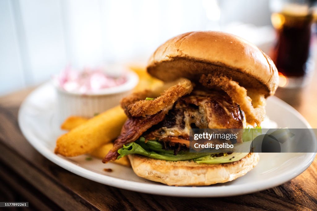 A Bacon Cheese Burger with onion rings shot in a brioche bun