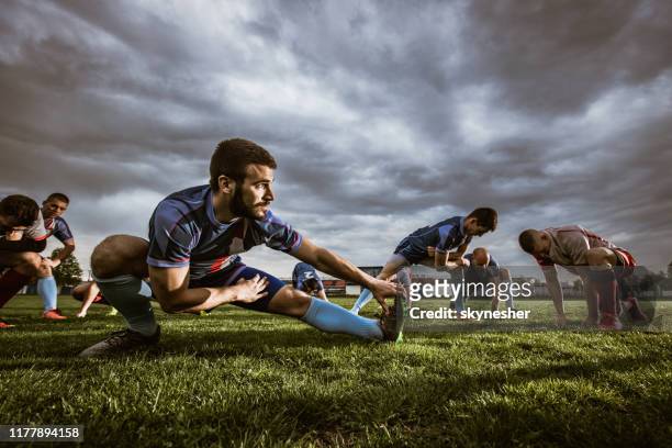 gruppe von sportlern, die dehnübungen auf einem stadion machen. - rugby liga stock-fotos und bilder