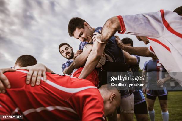 rugby-spieler, der sich bemüht, während er versucht, rivalen auf ein spiel zu übergeben. - rugby liga stock-fotos und bilder