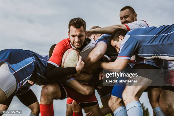 rugby players blocking their opponent on a match at playing field. - rugby league scrum stock pictures, royalty-free photos & images