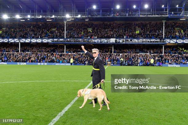 Former Everton player Dave Thomas and his guide dog receive applause during the half time break of the the Premier League match between Everton and...