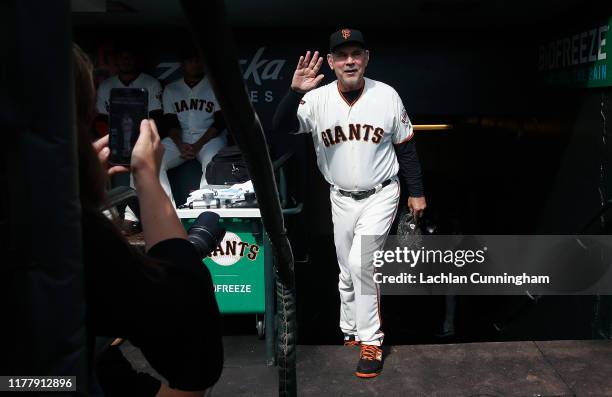 Manager Bruce Bochy of the San Francisco Giants acknowledges the fans as he walks into the dugout before his last game as Giants manager, the game...