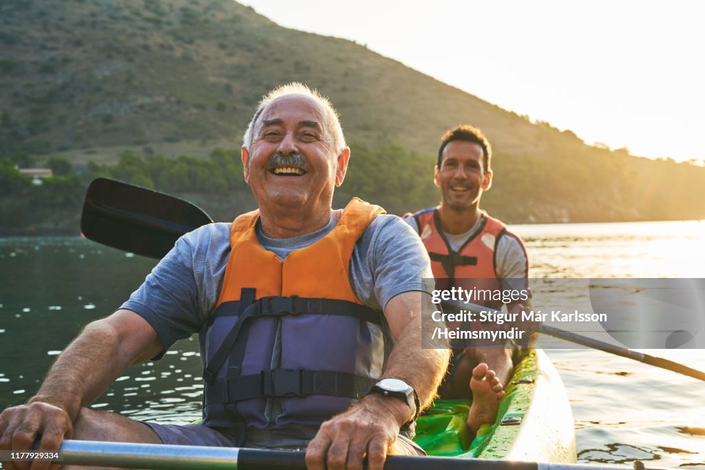Smiling father and son kayaking on river
