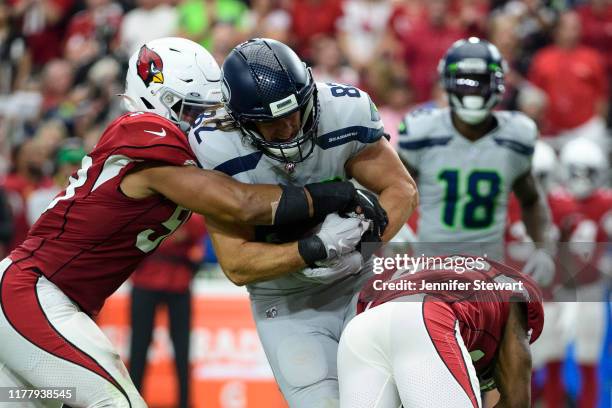 Tight end Luke Willson of the Seattle Seahawks carries the ball against middle linebacker Jordan Hicks and strong safety Budda Baker of the Arizona...