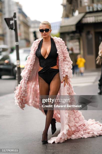 Caroline Vreeland wears sunglasses, a pink frilly dress, a black low neck top, tights, black shoes, outside Ralph & Russo, during Paris Fashion Week...