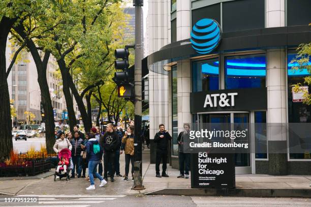 Pedestrians wait to cross a street in front of an AT&T Inc. Store in Chicago, Illinois, U.S., on Tuesday, Oct. 22, 2019. AT&T is scheduled to release...