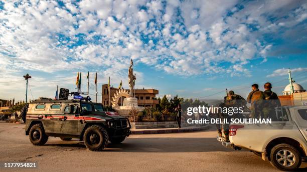 Members of the Syrian Kurdish Asayish internal security forces ride in the back of a pickup truck during a joint patrol with Russian military police...