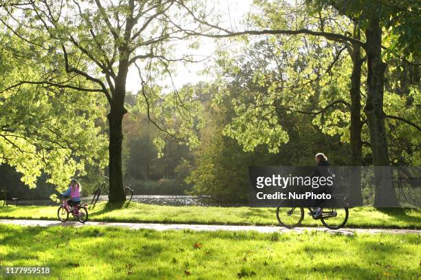 Woman with her daughter ride bicycles during the Autumn afternoon at the Rembrantd Park on October 24,2019 in Amsterdam,Netherlands.