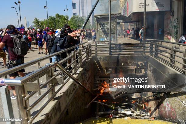 Demonstrators bring down a lamp post in Santiago on October 24, 2019 after a week of street violence which erupted against a now suspended metro fare...