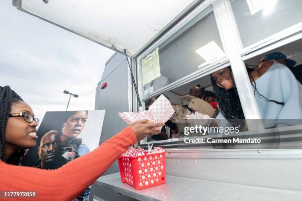 Nafessa Williams and Naomie Harris are seen serving from a food truck during the "Black & Blue" cast members' visit to Morehouse College on October...