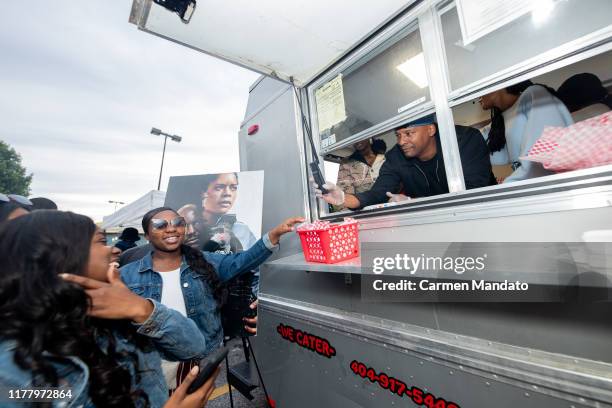 Deon Taylor and Naomie Harris are seen serving from a food truck during the "Black & Blue" cast members' visit to Morehouse College on October 24,...