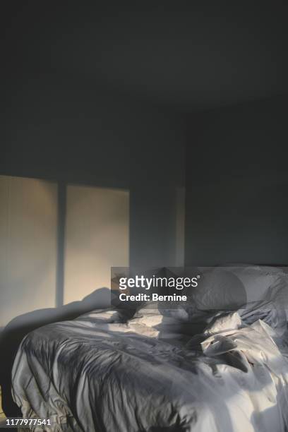 sunlight streaming in on an unmade bed - chambre vide photos et images de collection