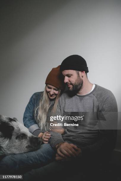 young couple sitting on floor with pet pig - traditionele koksmuts stockfoto's en -beelden