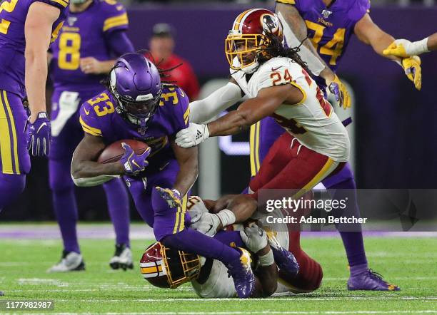 Jon Bostic and Josh Norman of the Washington Redskins tackles Dalvin Cook of the Minnesota Vikings in the fourth quarter at U.S. Bank Stadium on...