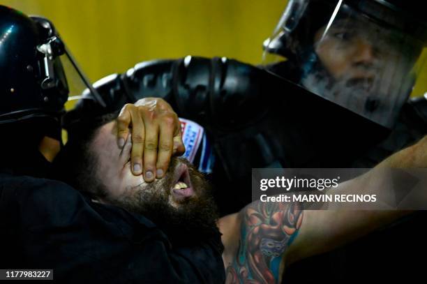 Motagua fan is subdued by the riot police during a Concacaf League football match at Cuscatlan Stadium in San Salvador on October 24, 2019.