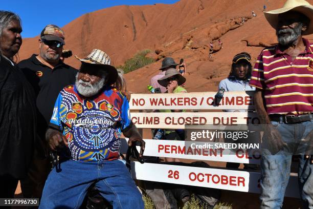 Aboriginal elders stand beside new signage at the base of Uluru, also known as Ayers Rock, ahead of the day's end marking the start of a permanent...